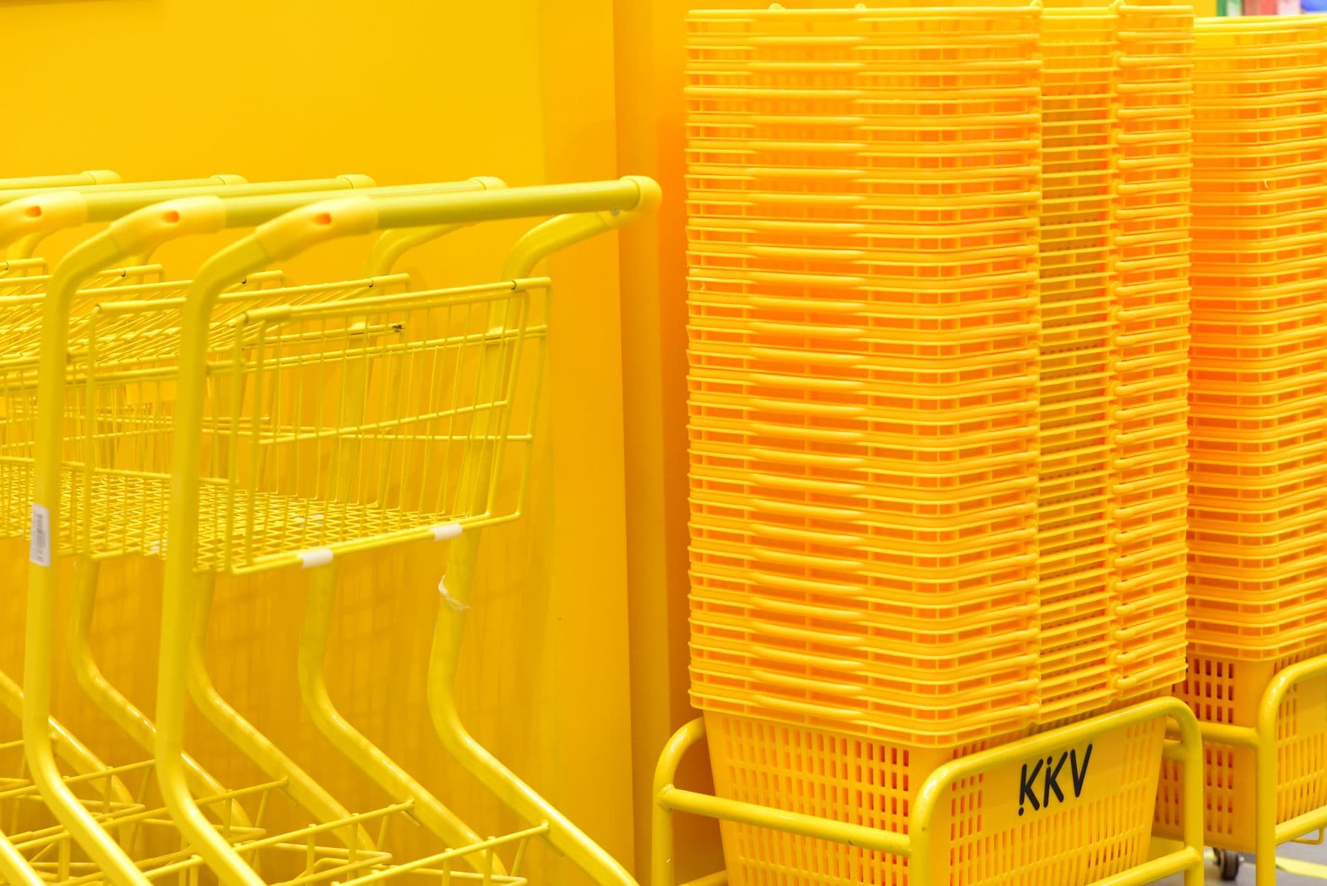 Stack of vibrant yellow shopping carts and baskets in a retail store aisle.