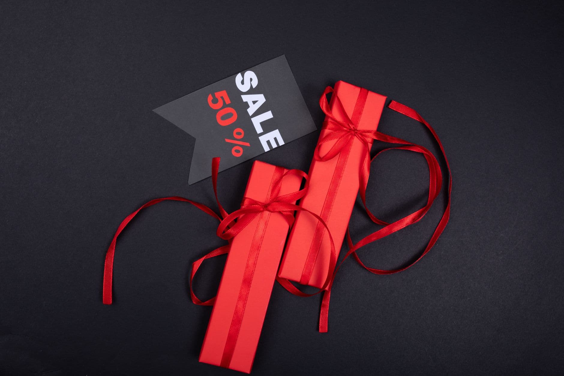 Red gift boxes wrapped with ribbons and a sale tag offer a festive discount vibe.